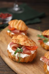 Photo of Delicious profiteroles with cream cheese, jamon and tomato on table, closeup