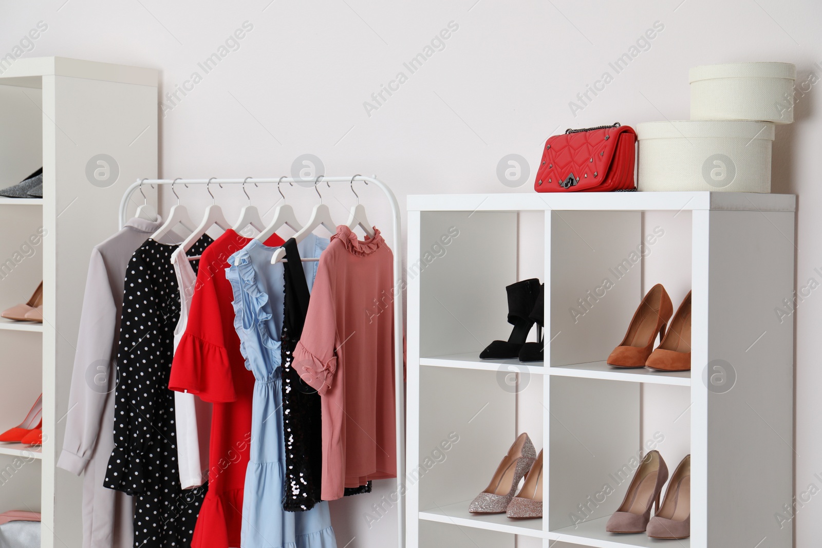 Photo of Wardrobe shelves with different stylish shoes and clothes indoors. Idea for interior design