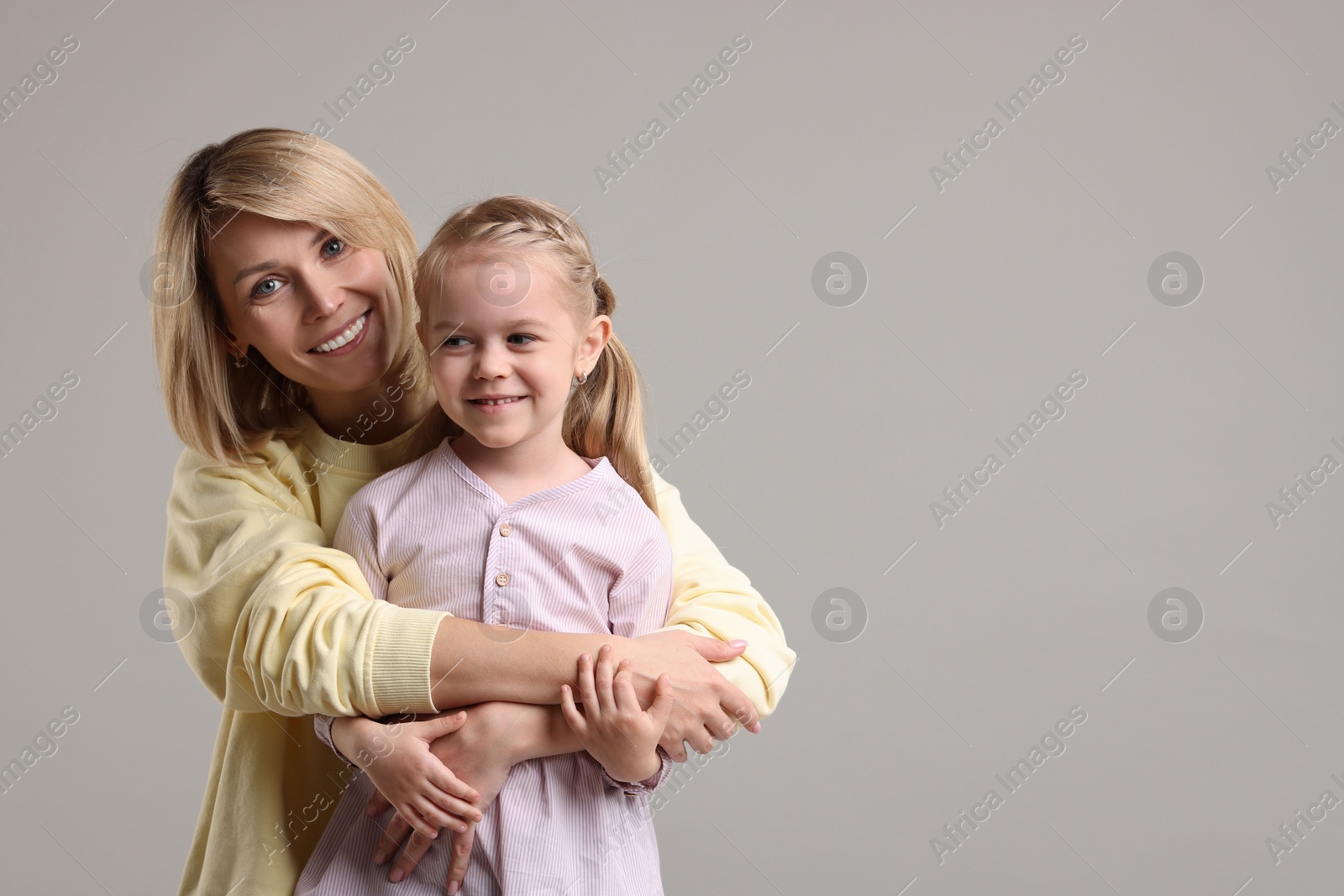 Photo of Family portrait of happy mother and daughter on grey background. Space for text