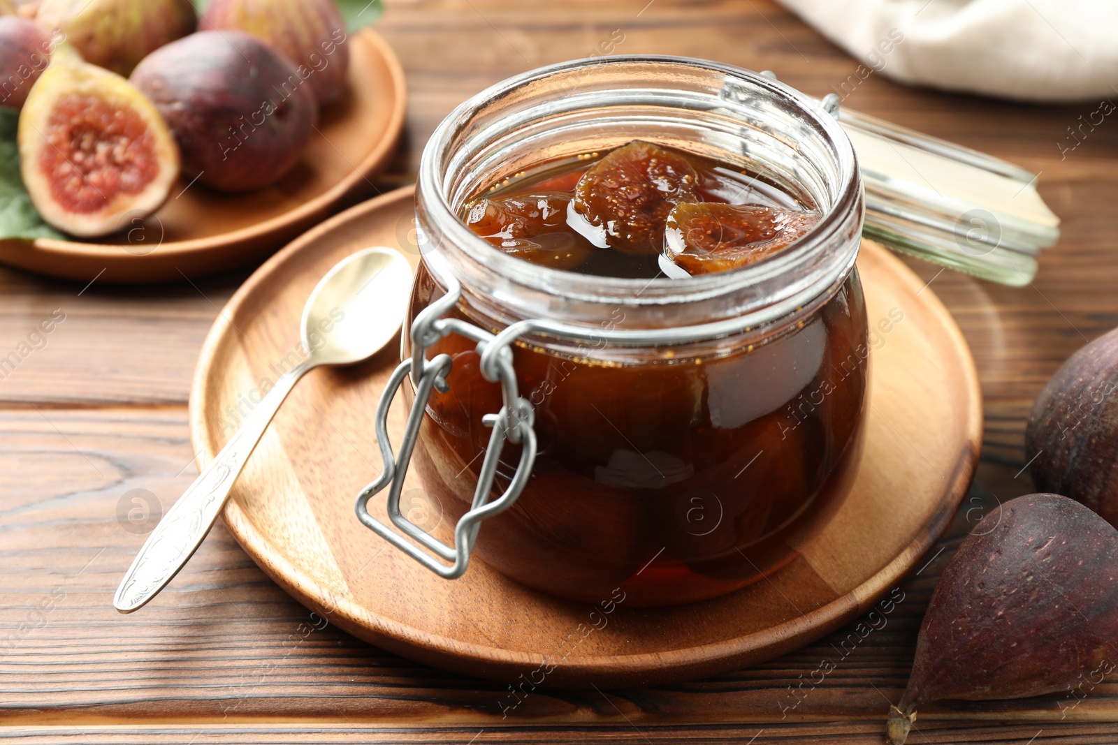 Photo of Jar of tasty sweet jam and fresh figs on wooden table