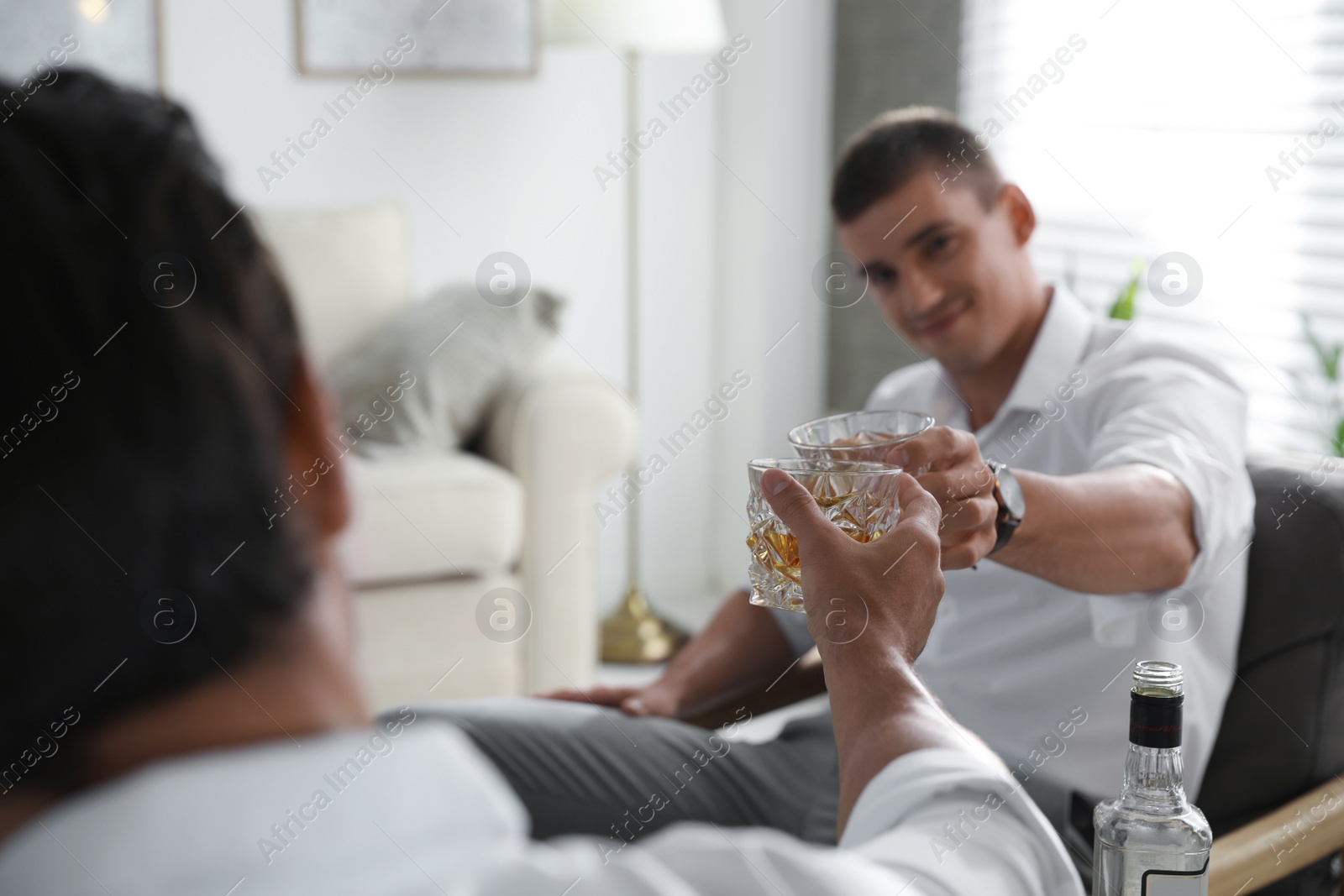 Photo of Young men drinking whiskey together at home