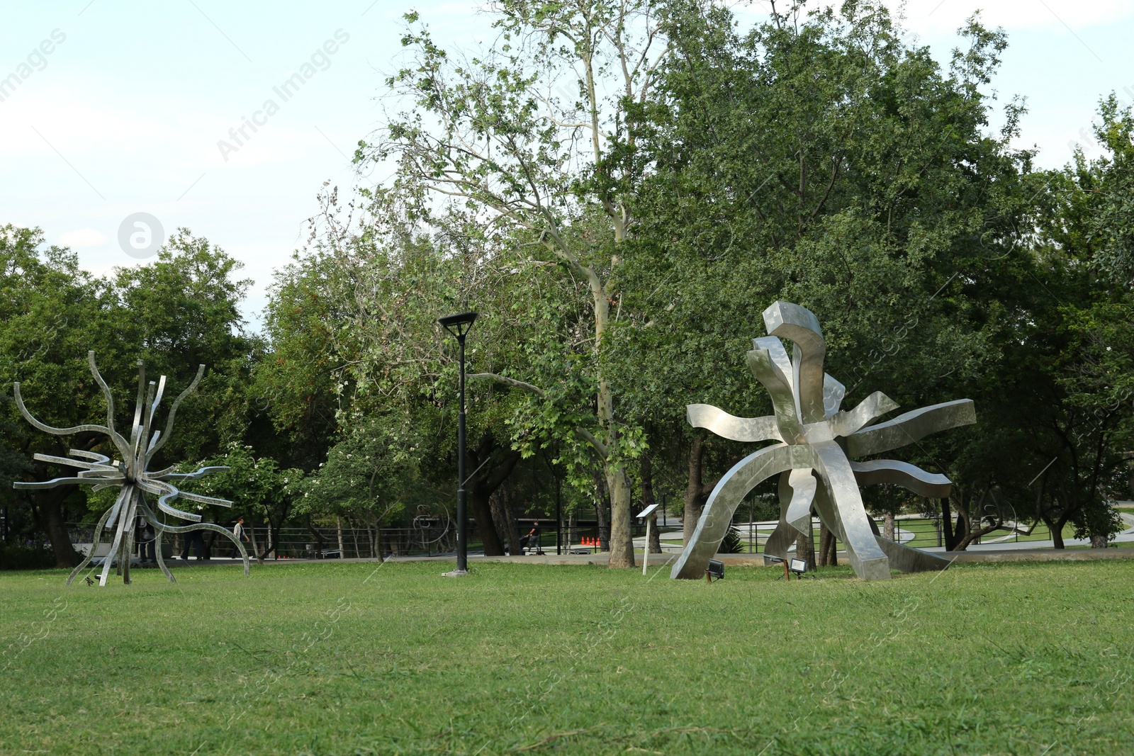 Photo of Picturesque view of beautiful park with metal figures on green grass