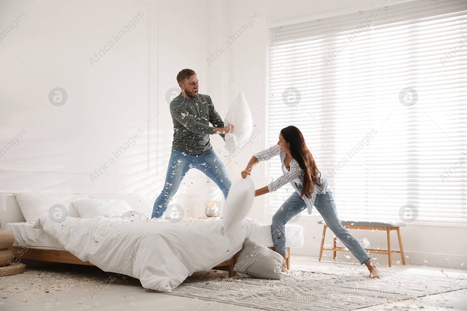 Photo of Happy young couple having fun pillow fight in bedroom