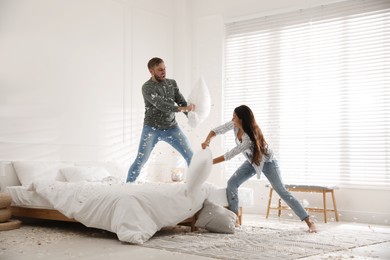 Happy young couple having fun pillow fight in bedroom