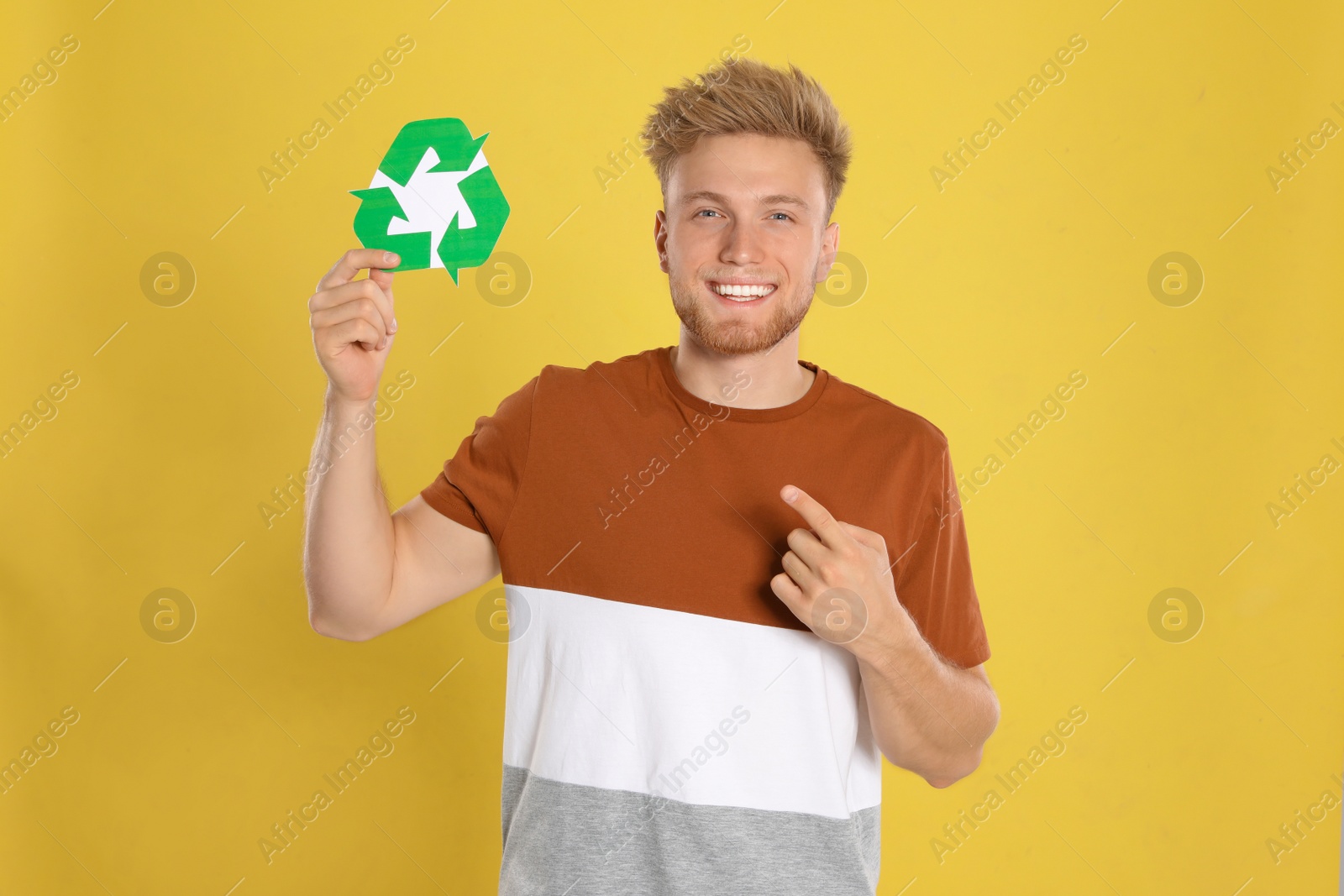 Photo of Young man with recycling symbol on yellow background