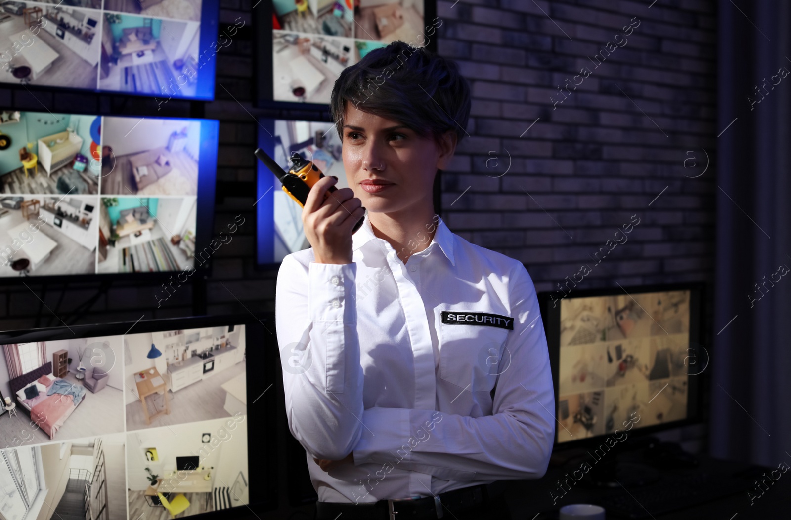 Photo of Female security guard with portable transmitter near cameras indoors