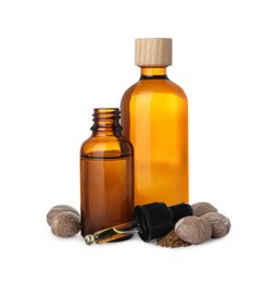 Photo of Bottles of nutmeg oil, nuts and pipette on white background
