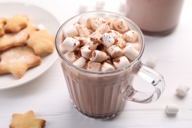 Photo of Cup of aromatic hot chocolate with marshmallows, cocoa powder and tasty cookies on white table, closeup