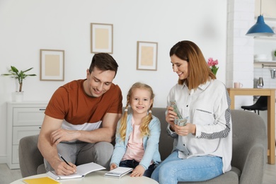 Happy family counting money on sofa at home