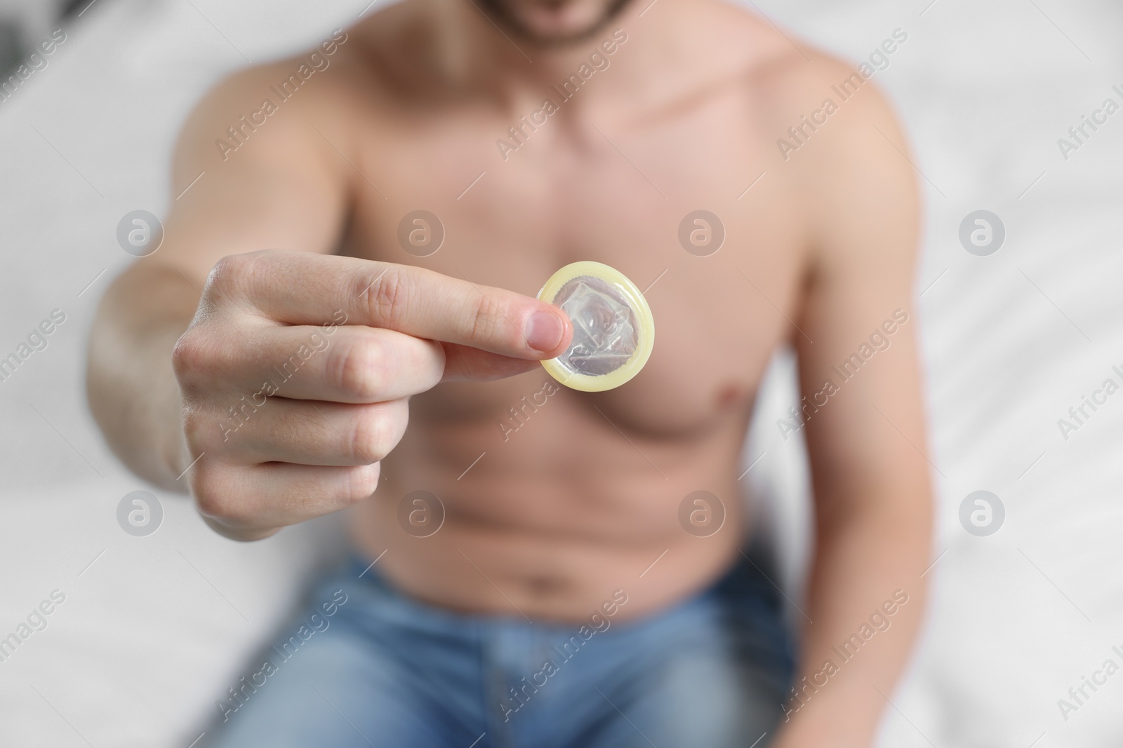 Photo of Closeup view of man showing condom on bed