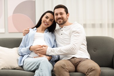 Photo of Portrait of happy pregnant woman with her husband on sofa at home