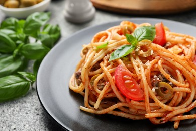 Photo of Delicious pasta with anchovies, tomatoes and olives on table, closeup