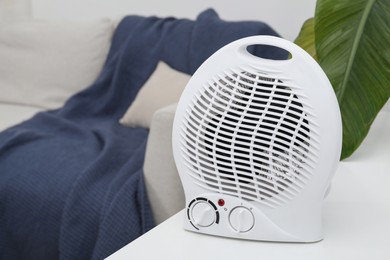Portable electric fan heater near sofa indoors