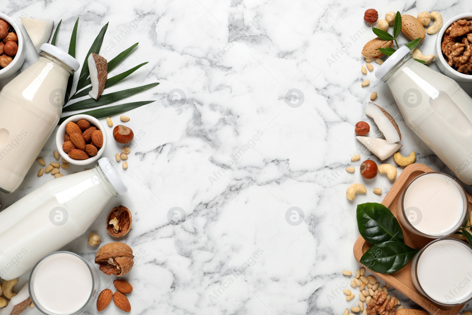 Photo of Vegan milk and different nuts on white marble table, flat lay. Space for text