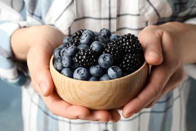 Woman with bowl of delicious summer berries, closeup