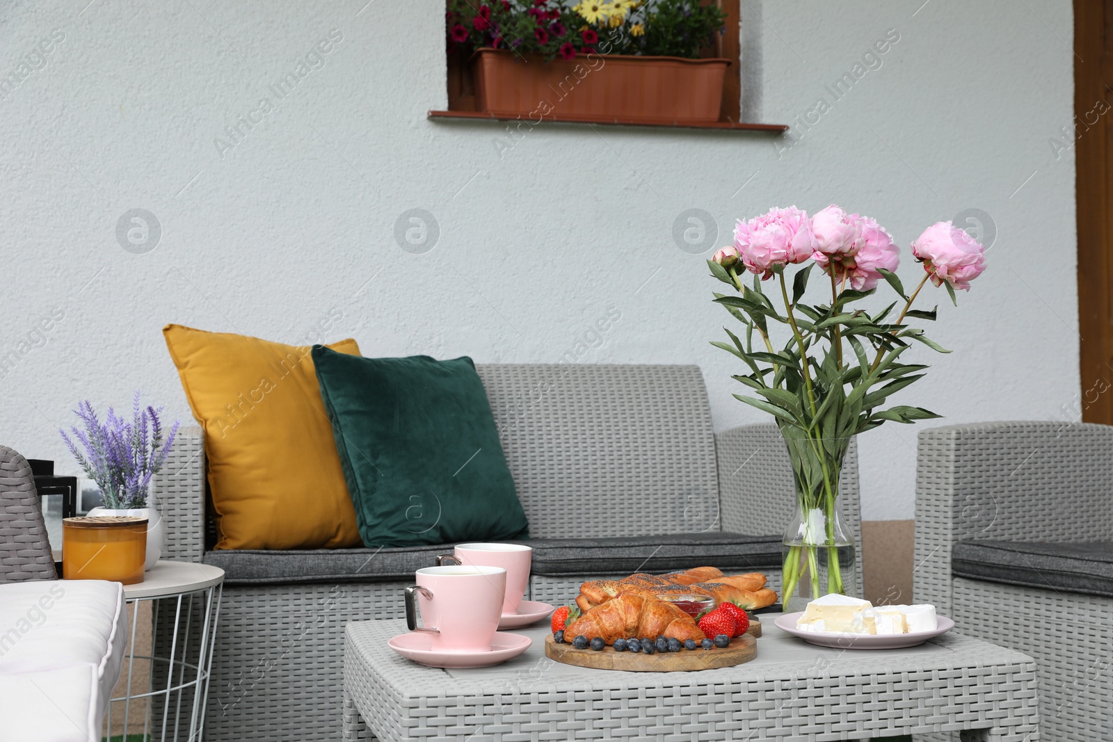 Morning drink, pastry, berries, cheese and vase with flowers on rattan table. Summer breakfast on terrace Photo of Morning drink, pastry, berries, cheese and vase with flowers on rattan table. Summer breakfast on terrace