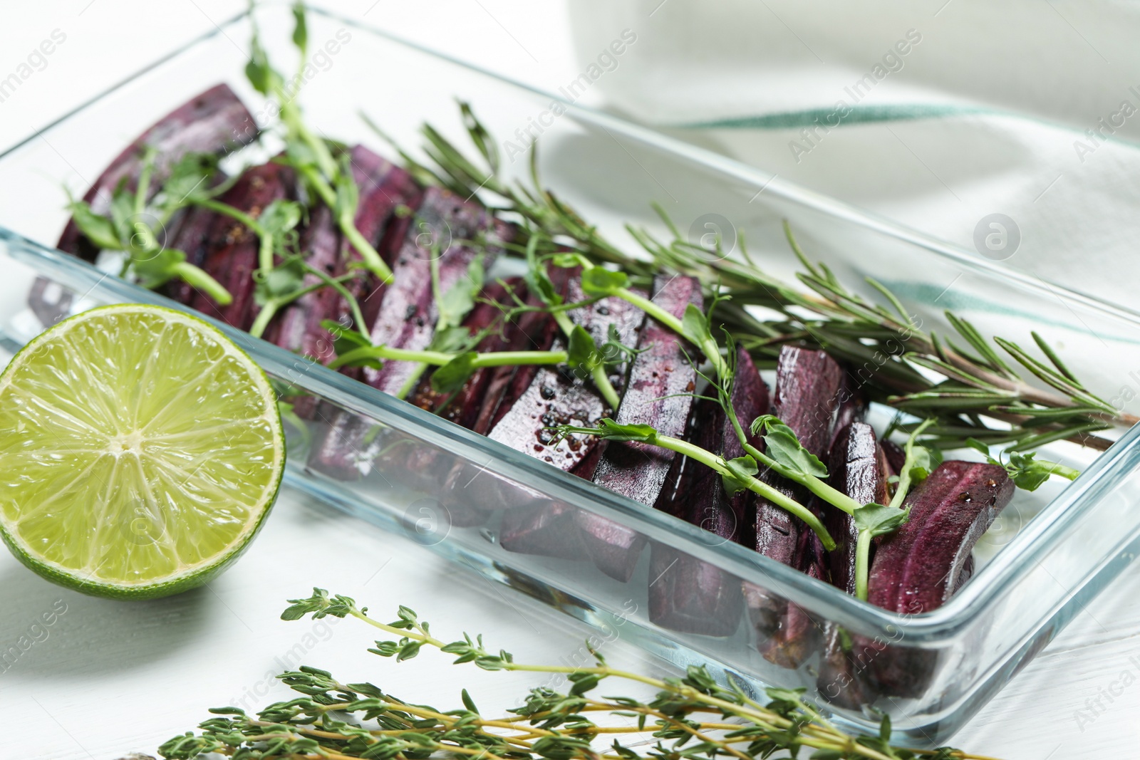 Photo of Raw black carrot with sprouts and lime on white table, closeup