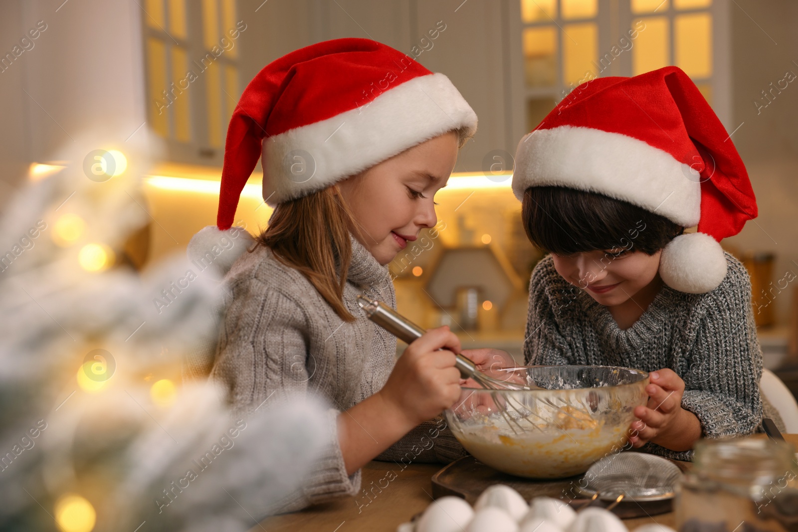 Photo of Cute little children making dough for Christmas cookies in kitchen