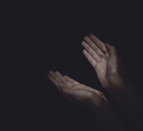 Image of Christian woman praying in darkness, closeup. Space for text