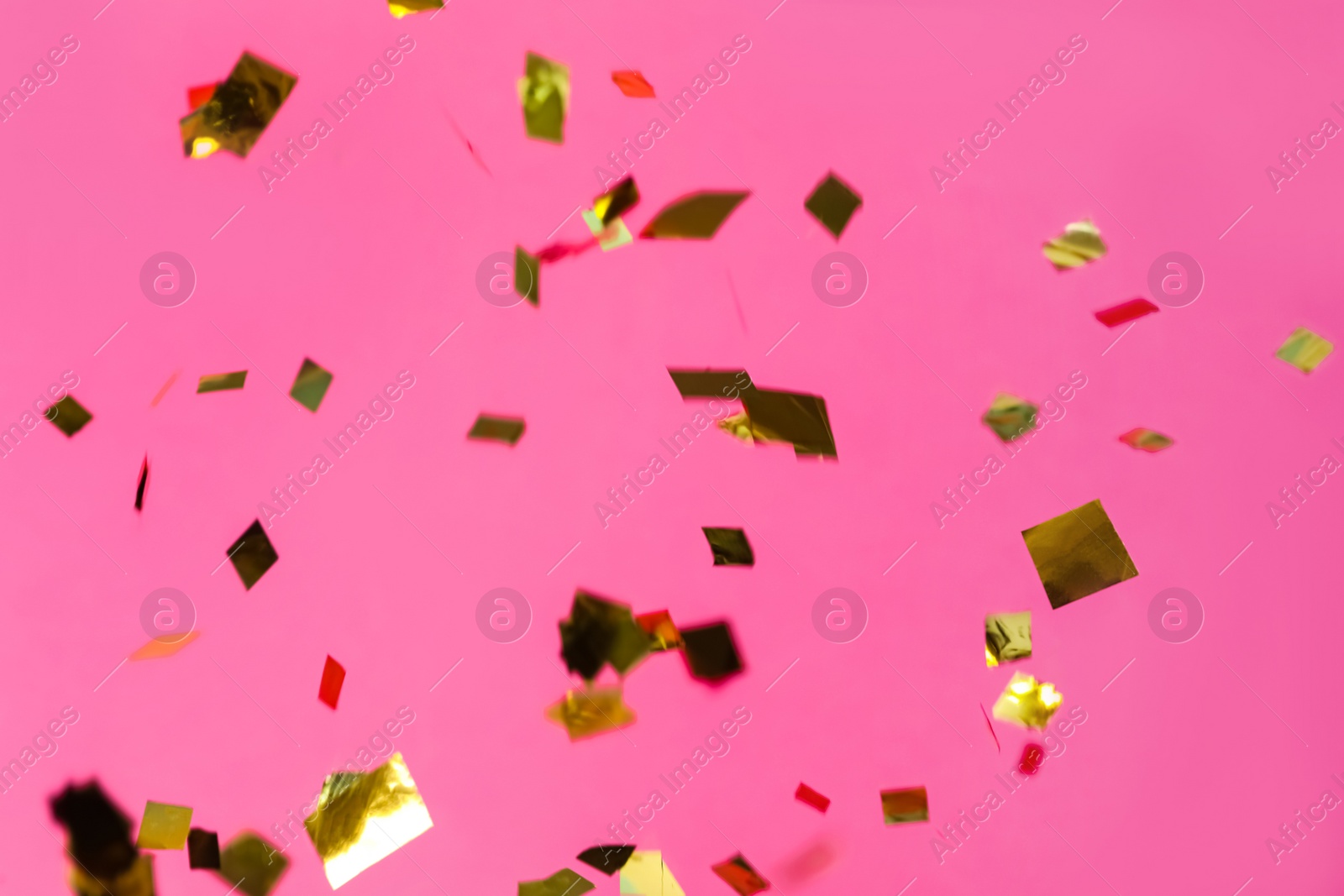 Photo of Shiny golden confetti falling down on pink background