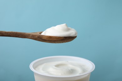 Photo of Eating delicious natural yogurt on light blue background