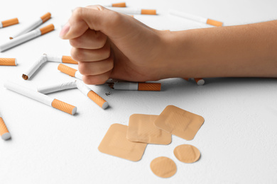 Photo of Nicotine patches and woman breaking cigarettes at white table, closeup