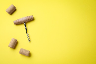 Photo of Corkscrew and wine bottle stoppers on yellow background, flat lay. Space for text
