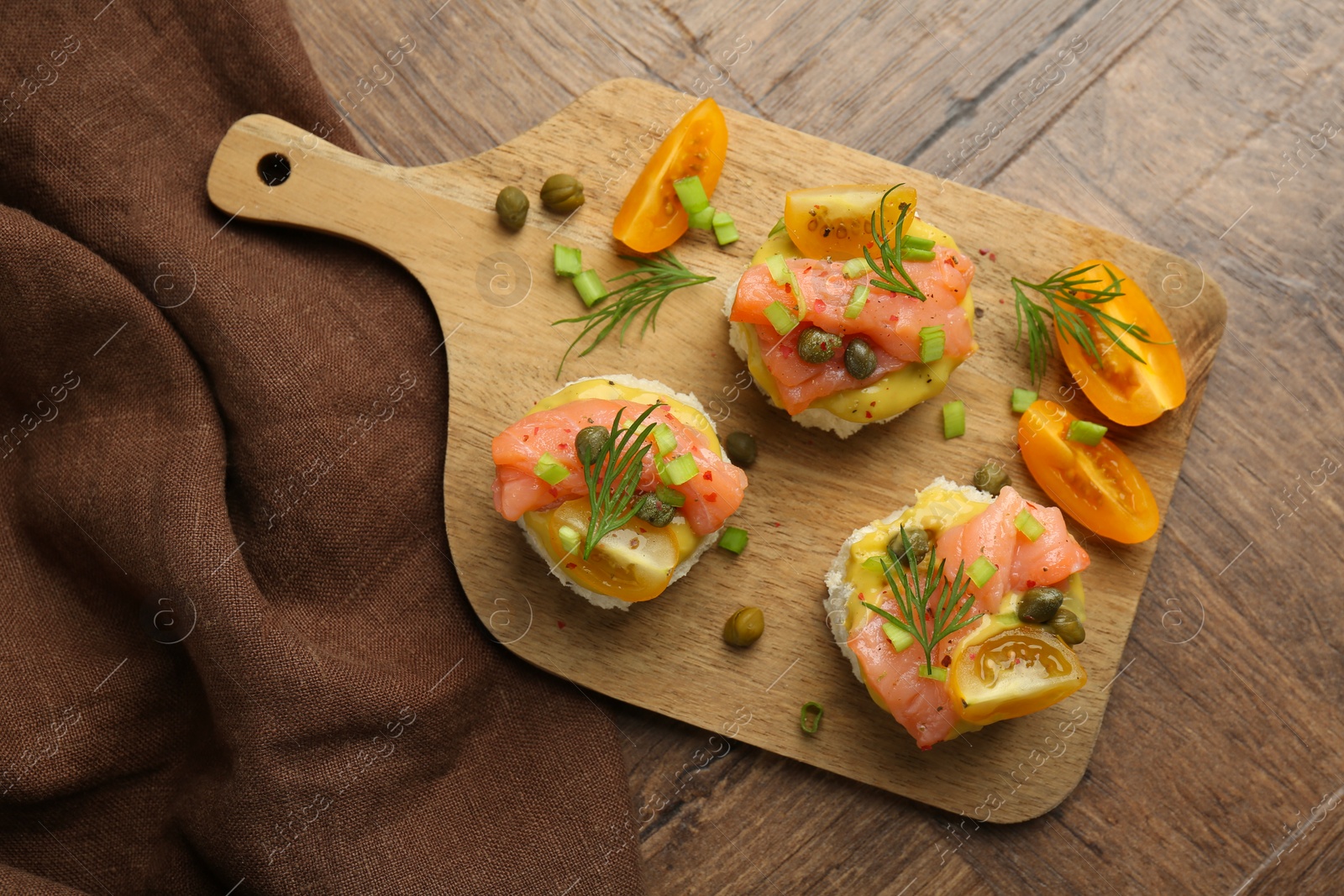 Photo of Tasty canapes with salmon served on wooden table, top view