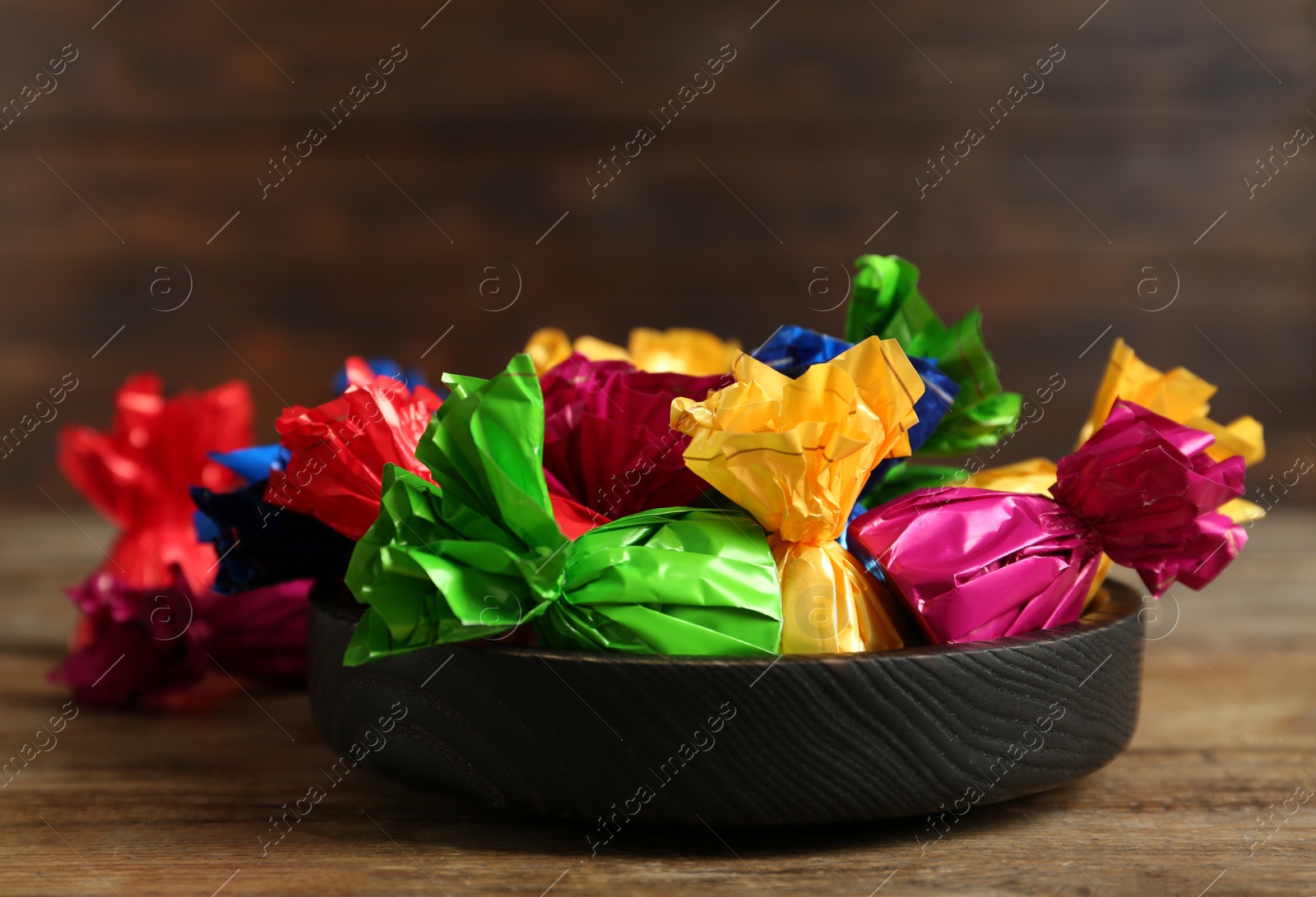 Photo of Candies in colorful wrappers on wooden table