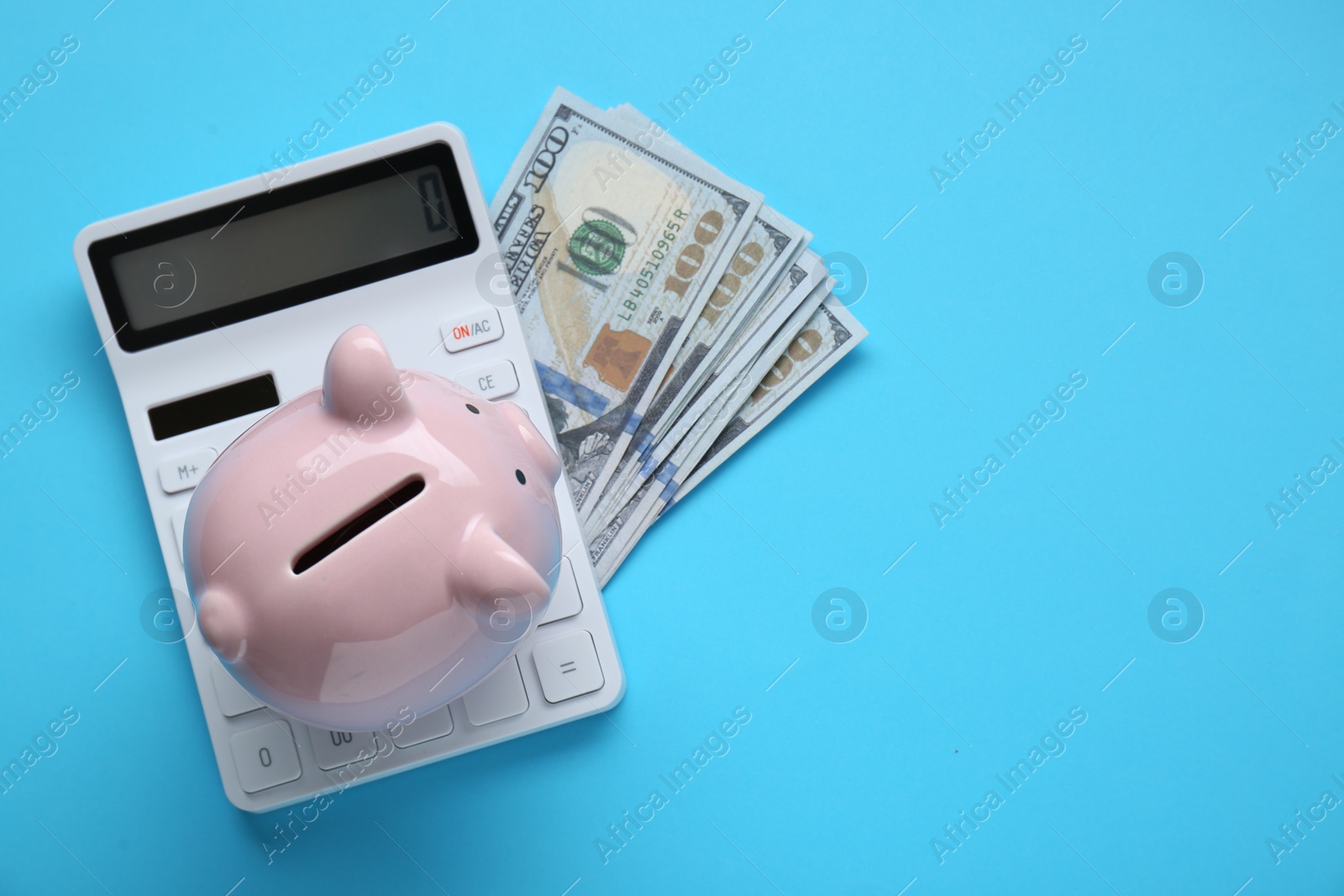 Photo of Piggy bank, calculator and banknotes on light blue background, flat lay. Space for text