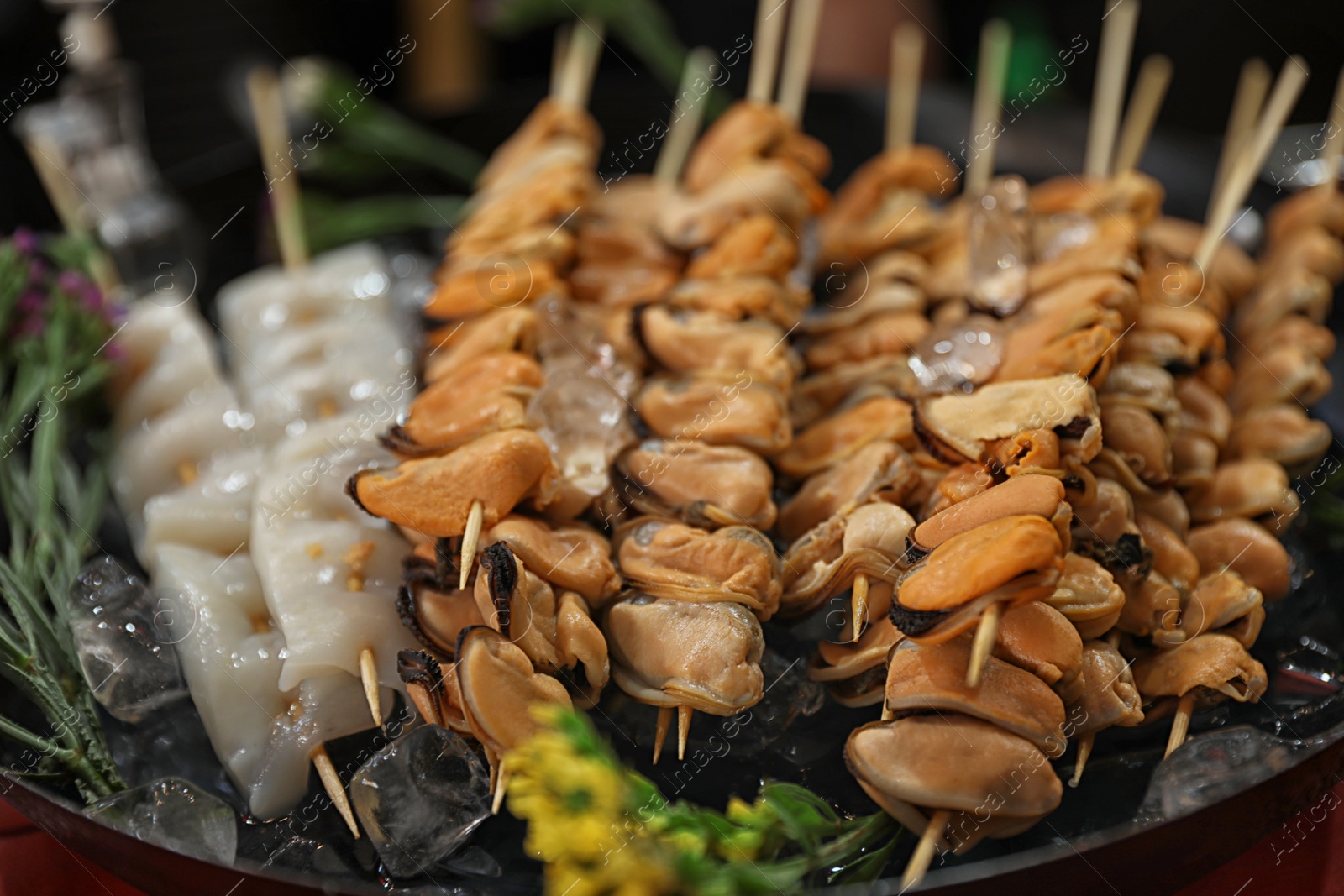 Photo of Seafood skewers served in dish with ice, closeup