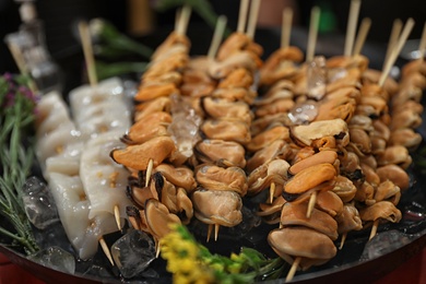 Photo of Seafood skewers served in dish with ice, closeup