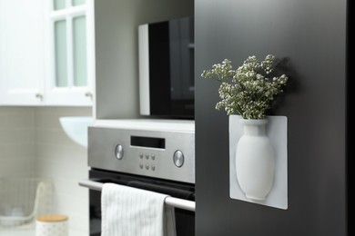 Photo of Silicone vase with beautiful gypsophila flowers on fridge in kitchen, space for text