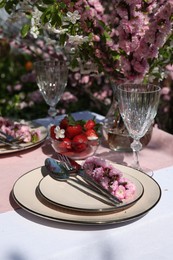 Stylish table setting with beautiful spring flowers in garden