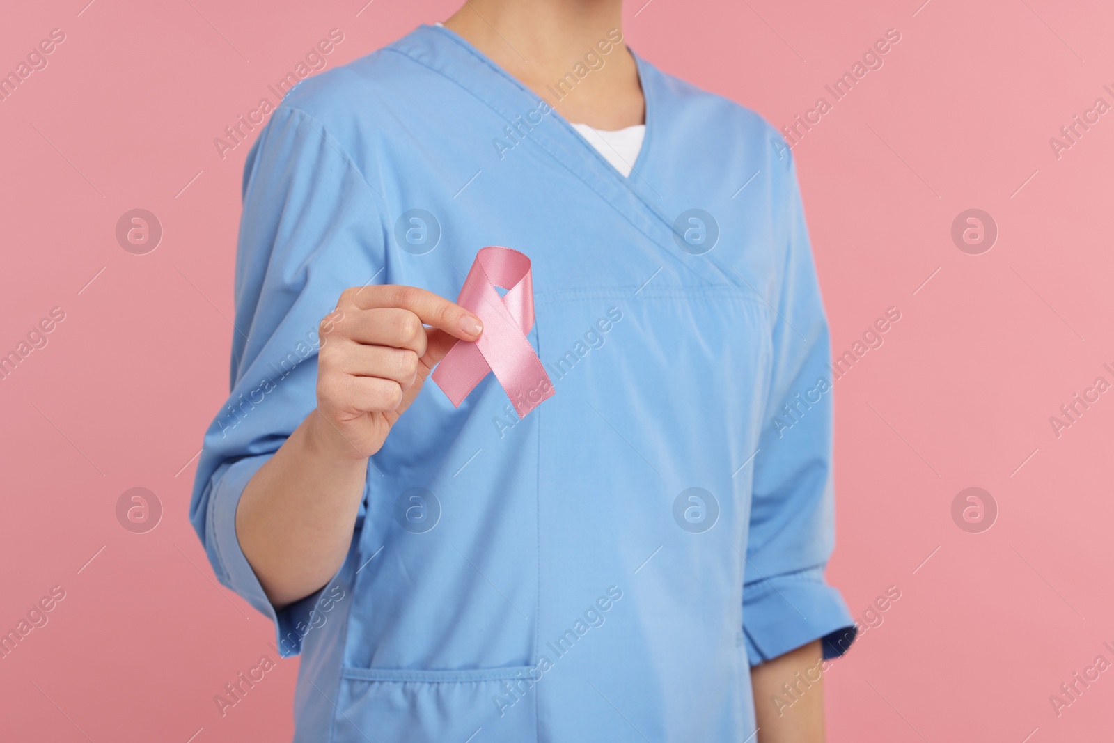 Photo of Mammologist with pink ribbon on color background, closeup. Breast cancer awareness