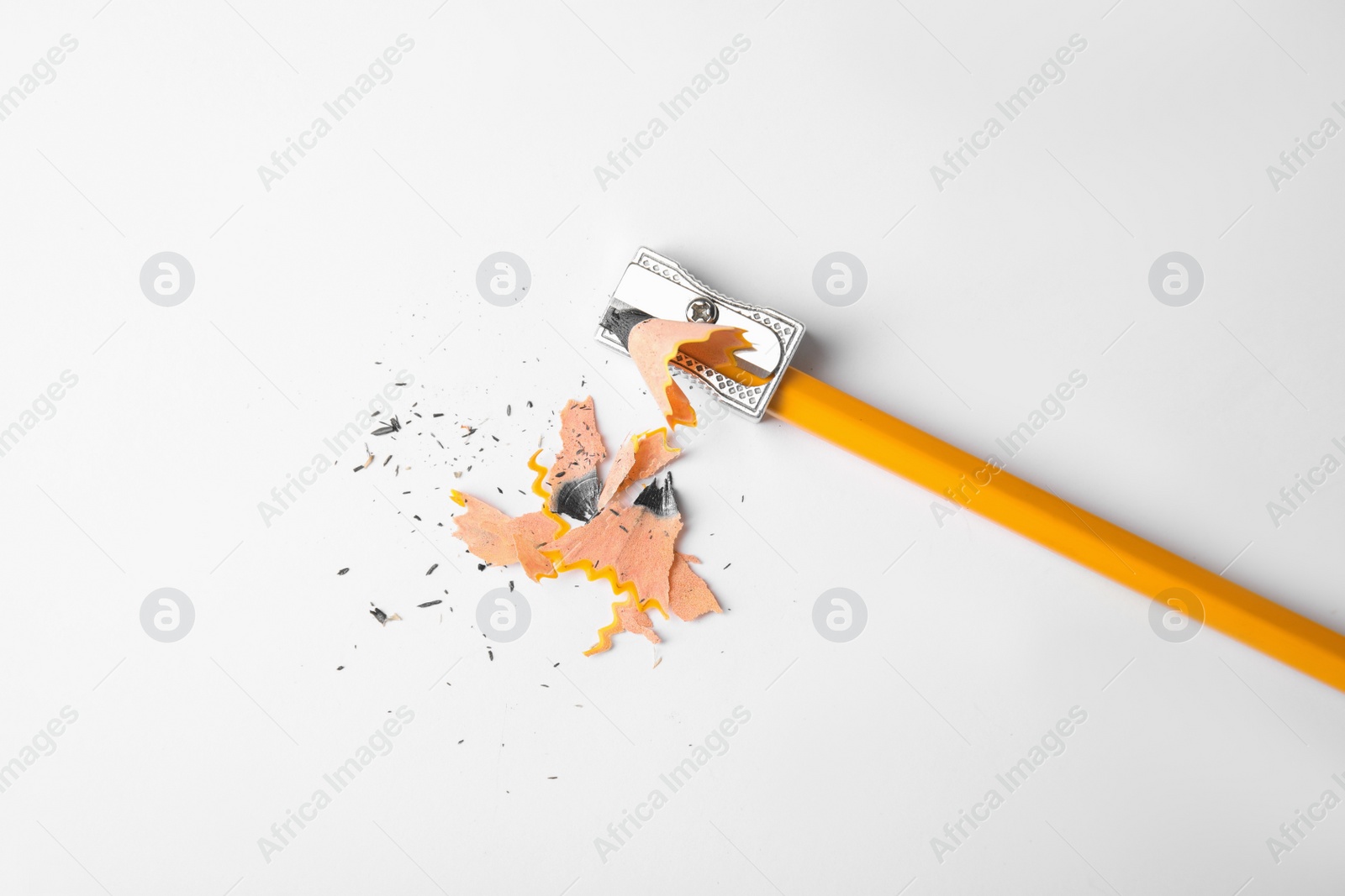 Photo of Graphite pencil, shavings and sharpener on white background, top view