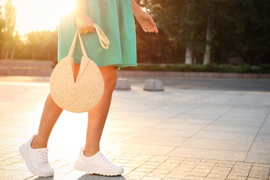 Young woman with stylish straw bag outdoors, closeup. Space for text