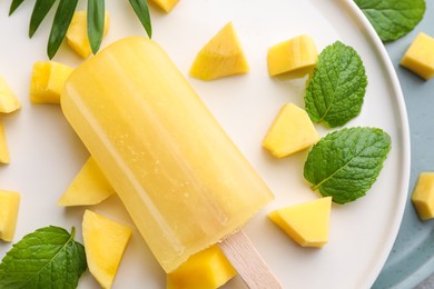 Photo of Tasty mango ice pop on white plate, closeup. Fruit popsicle