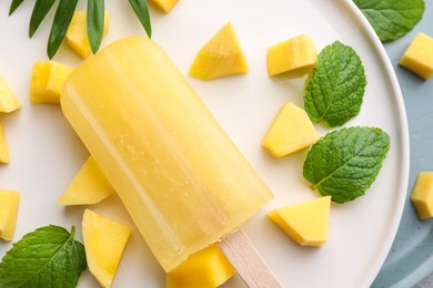 Tasty mango ice pop on white plate, closeup. Fruit popsicle