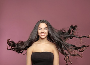 Portrait of beautiful model with gorgeous curly hair on color background