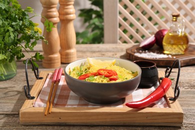 Photo of Stir-fry. Tasty noodles with vegetables and meat in bowl served on wooden table