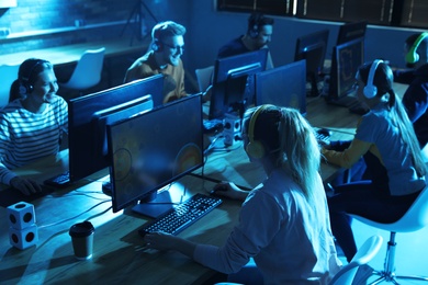 Photo of Group of people playing video games in internet cafe