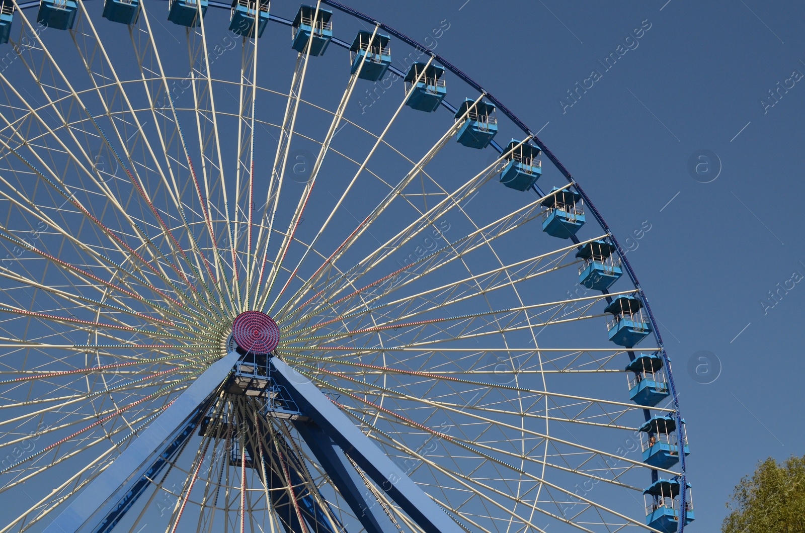 Photo of Amusement park. Beautiful Ferris wheel against blue sky, low angle view