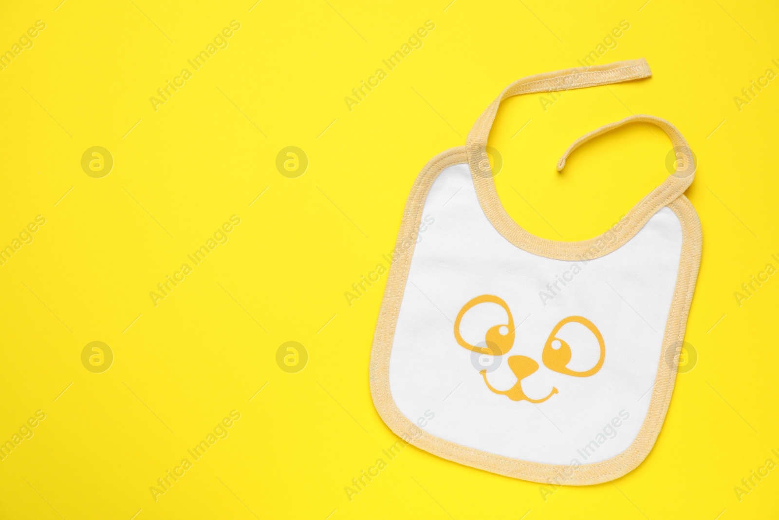 Photo of New baby bib on yellow background, top view. Space for text