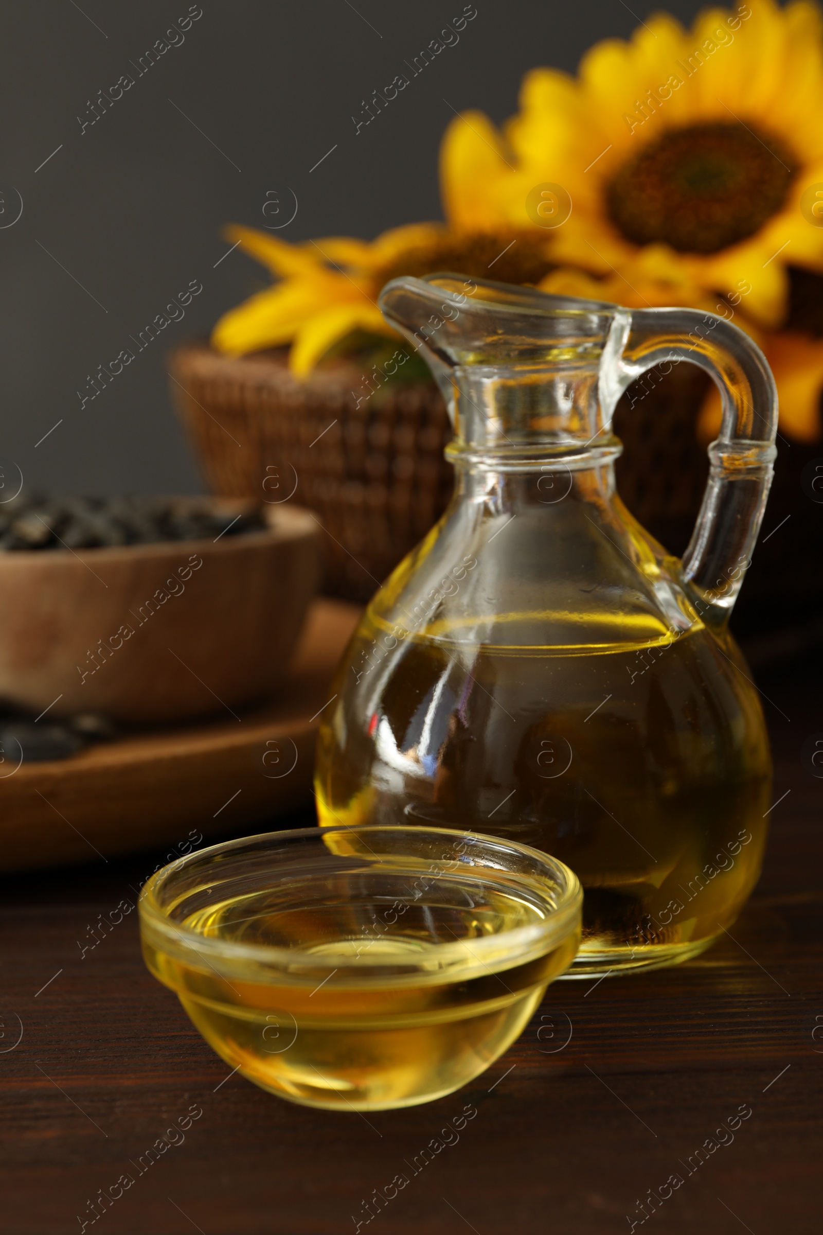 Photo of Sunflower oil in glass bowl and jug on wooden table