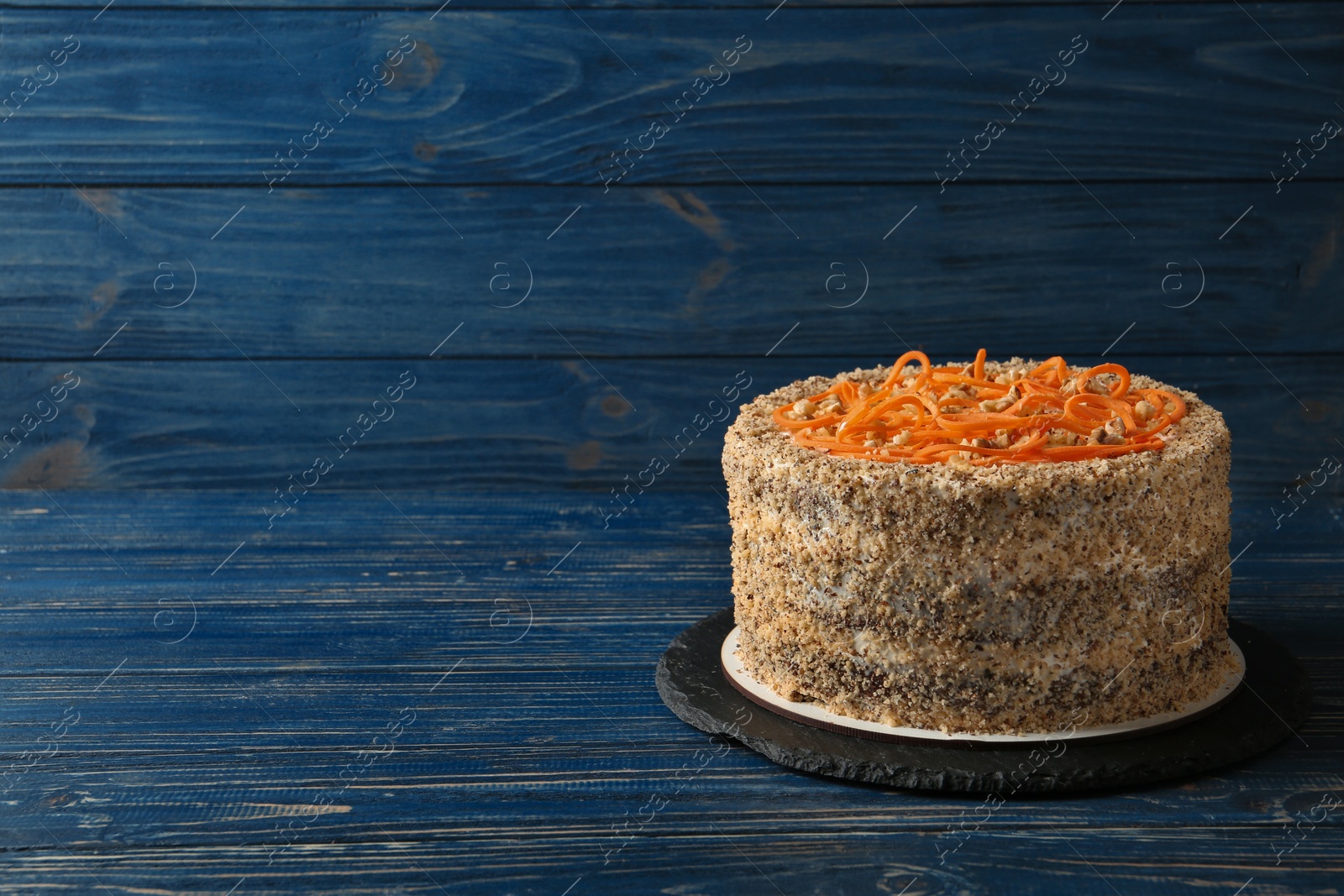 Photo of Dish with delicious carrot cake on blue wooden background. Space for text