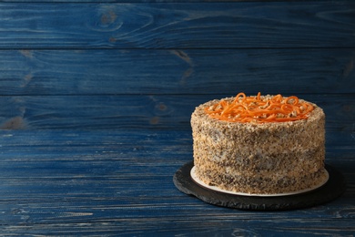 Photo of Dish with delicious carrot cake on blue wooden background. Space for text