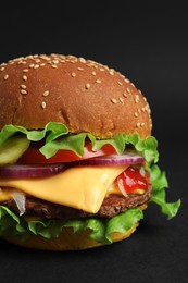 Delicious burger with beef patty and lettuce on dark background, closeup
