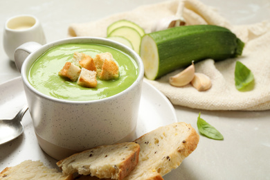 Photo of Tasty homemade zucchini cream soup served on light table