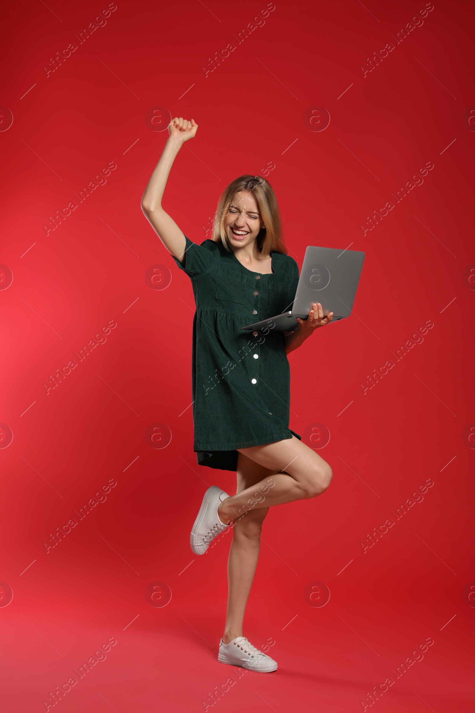 Photo of Full length portrait of emotional woman with modern laptop on red background